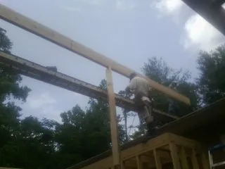 Carpenter setting a ridge beam over a new addition frame — Ice Dam Removal by Roofing Brothers in Brooks
