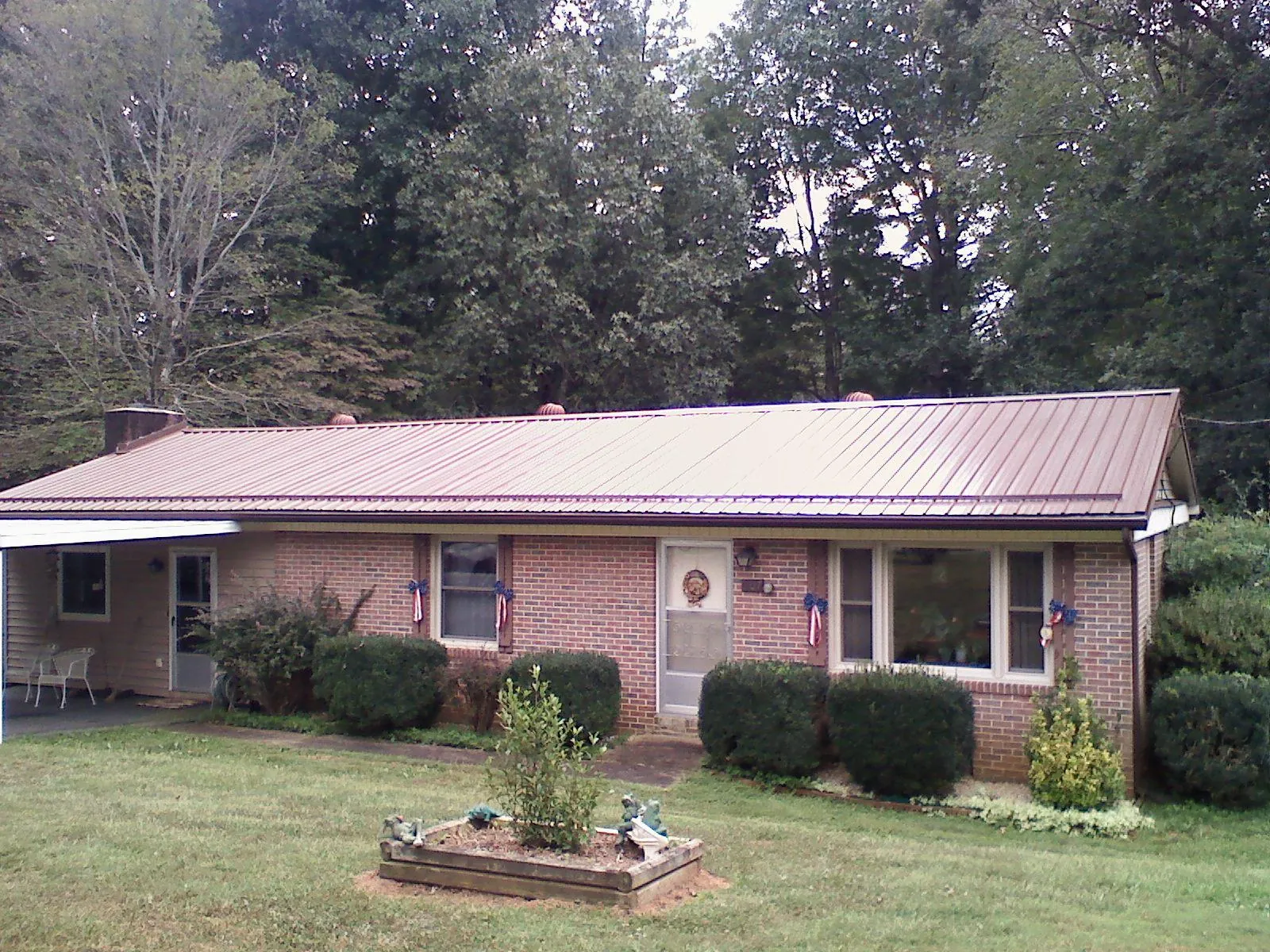 Bronze metal roof on a brick ranch home with a carport in Brooks