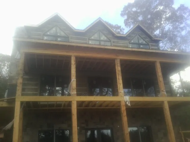 Dormers and porch framing on a large log home under construction — Roof Coating work by our crew in Brooks