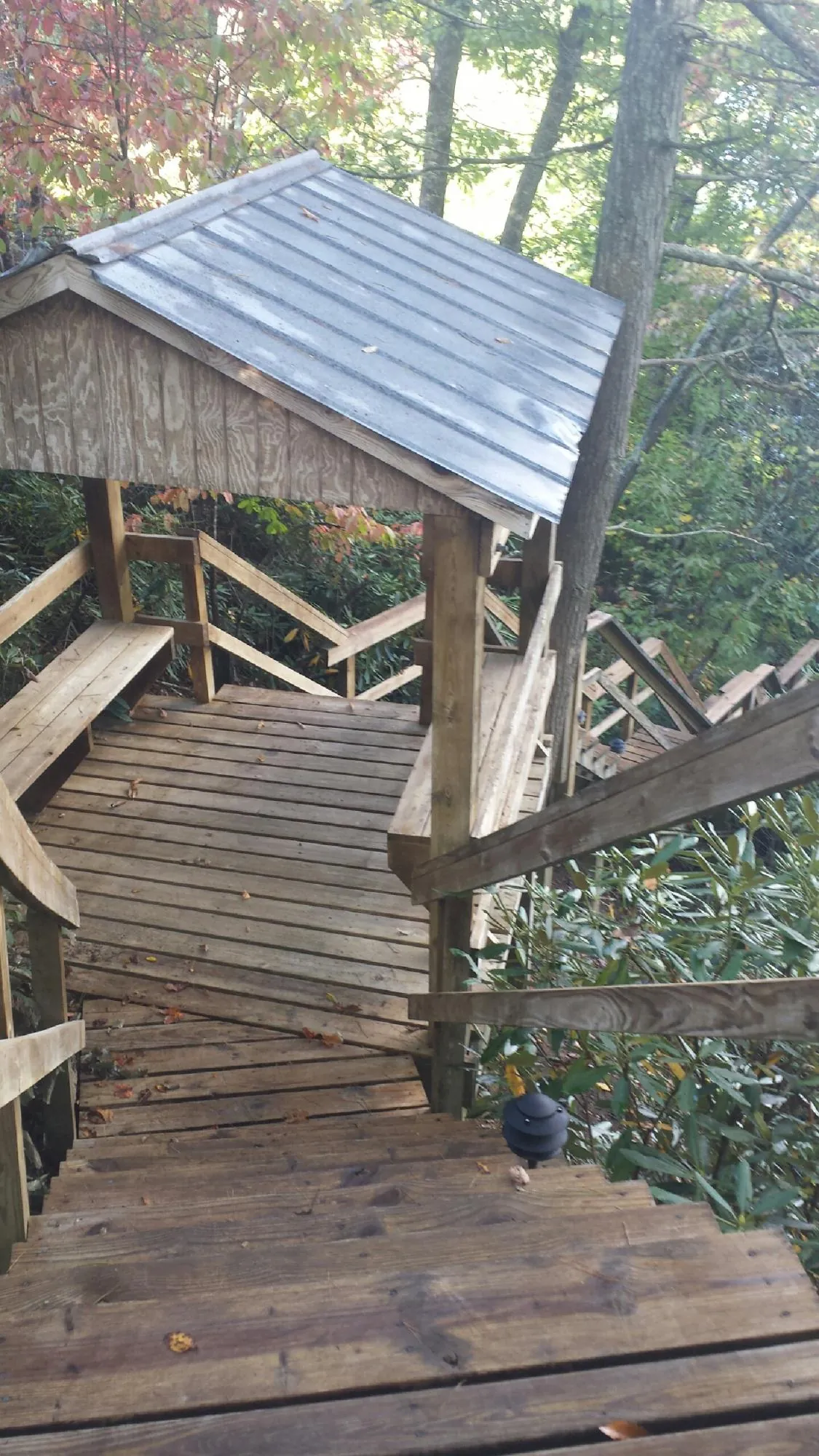 Metal roofed shelter over wooden steps on a wooded walkway — Skylight Repair & Installation work by our crew in Brooks